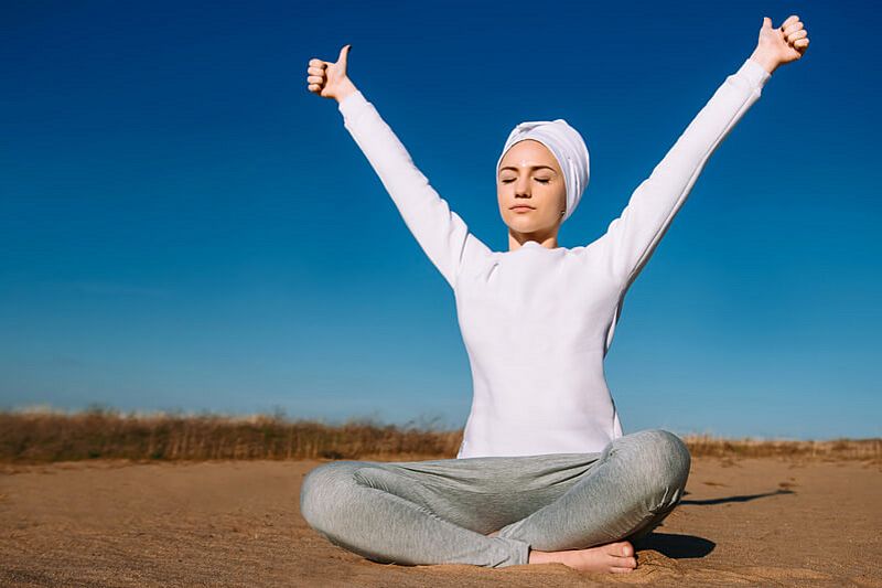 Frau praktiziert Kundalini Yoga im Freien