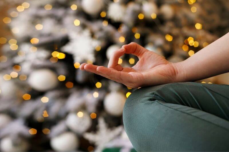 Yoga und Weihnachten: Frau meditiert vor Weihnachtsbaum