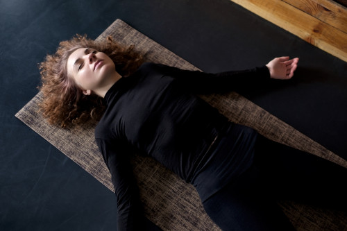 Bild einer Frau, die Shavasana übt